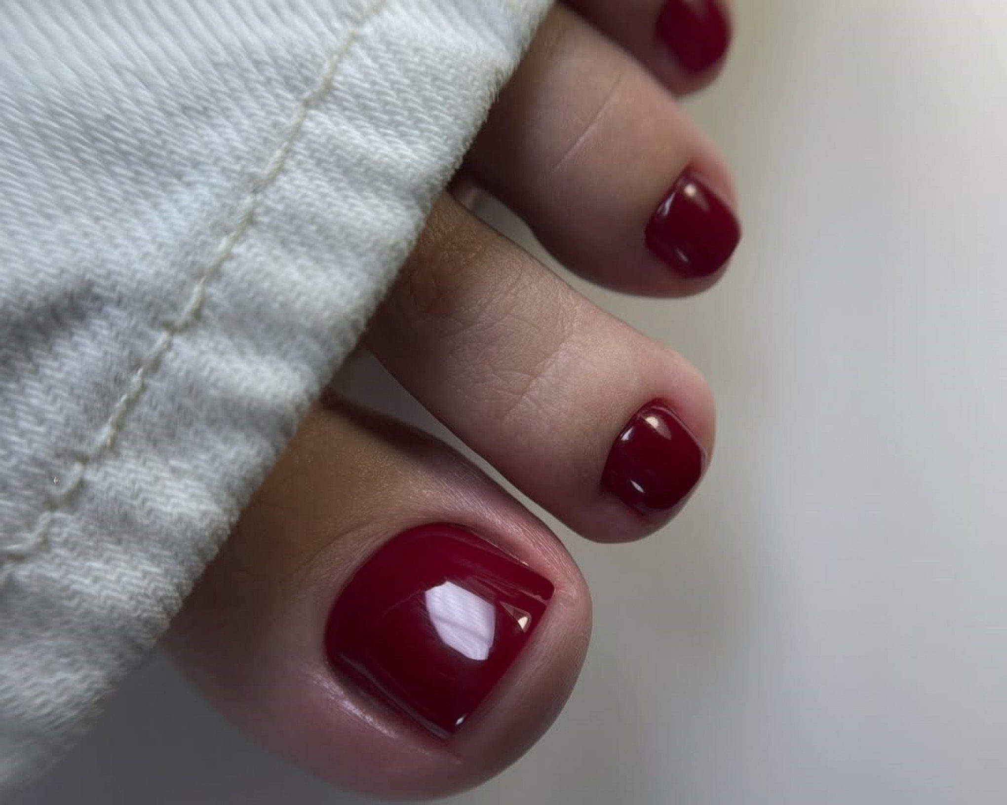 Deep Red Glossy Toes Against White — Winter Toe Nails