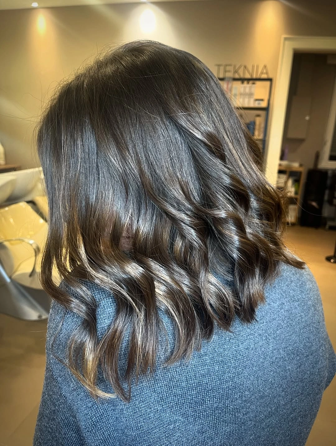 Dark shoulder-length hair with smooth top and broad lower curls