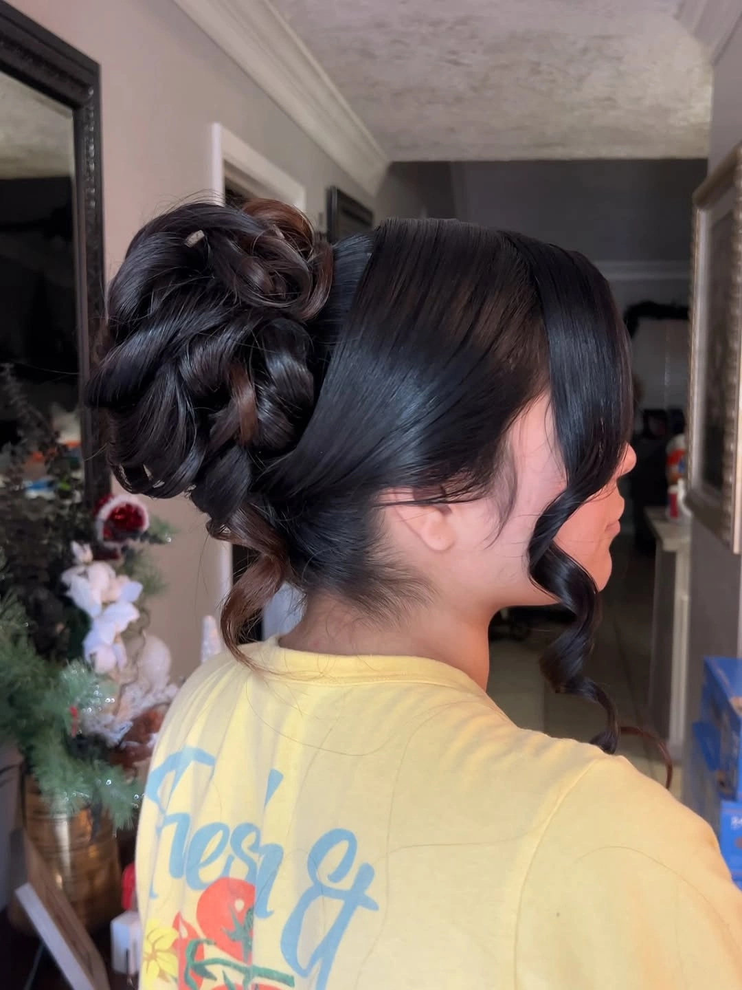 Dark high looped bun with one long curled face-framing section