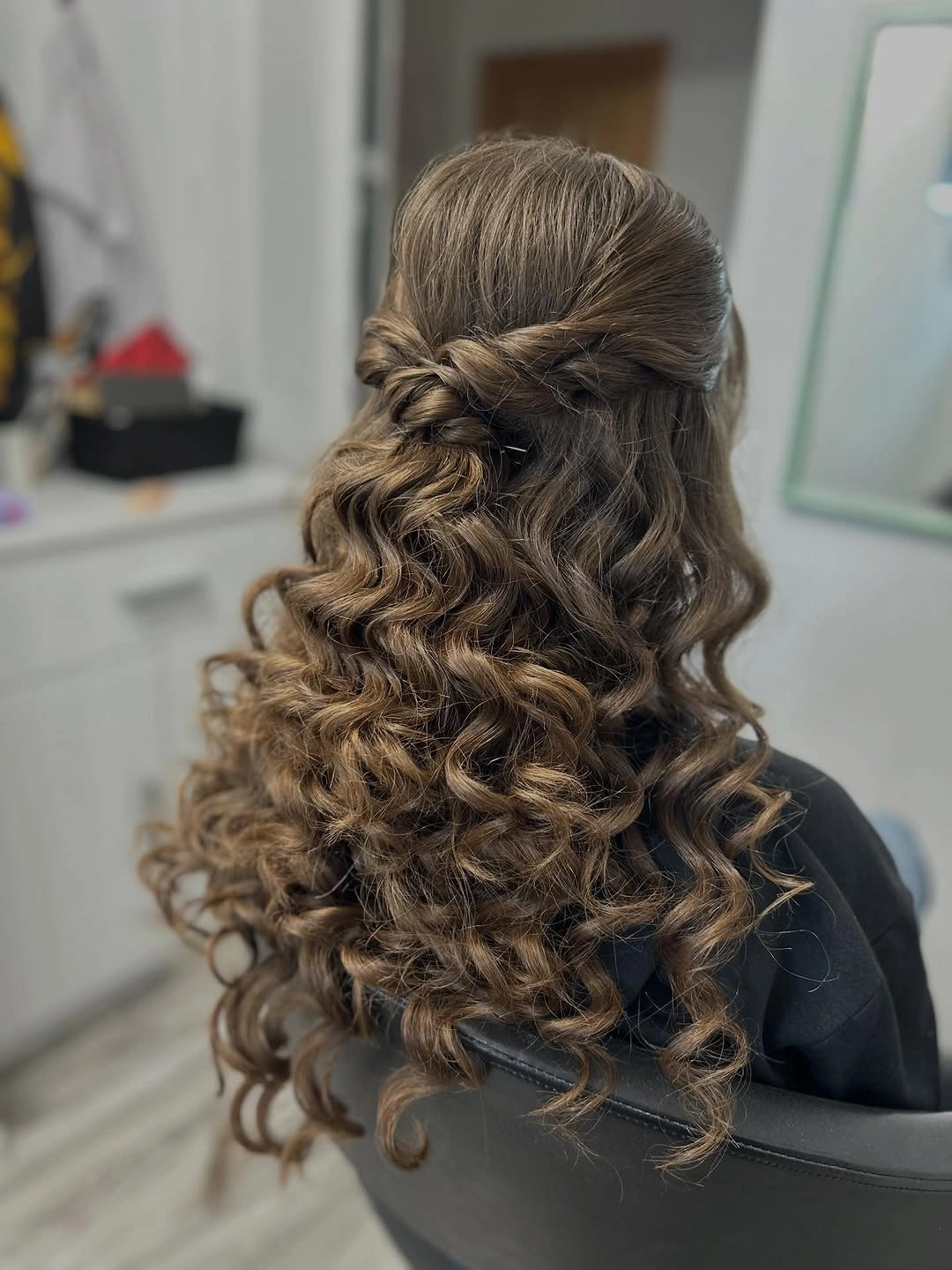 Brown half-up hairstyle with twisted sides and defined cascading curls