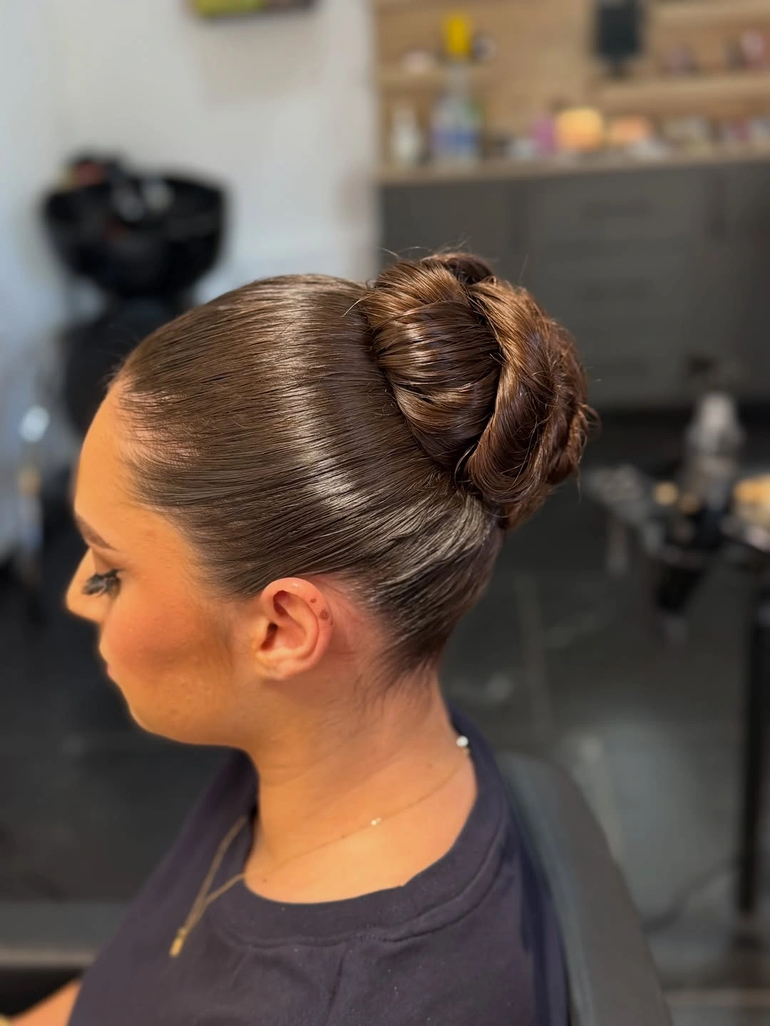 Sleek brown hair gathered into a high rounded wrapped bun