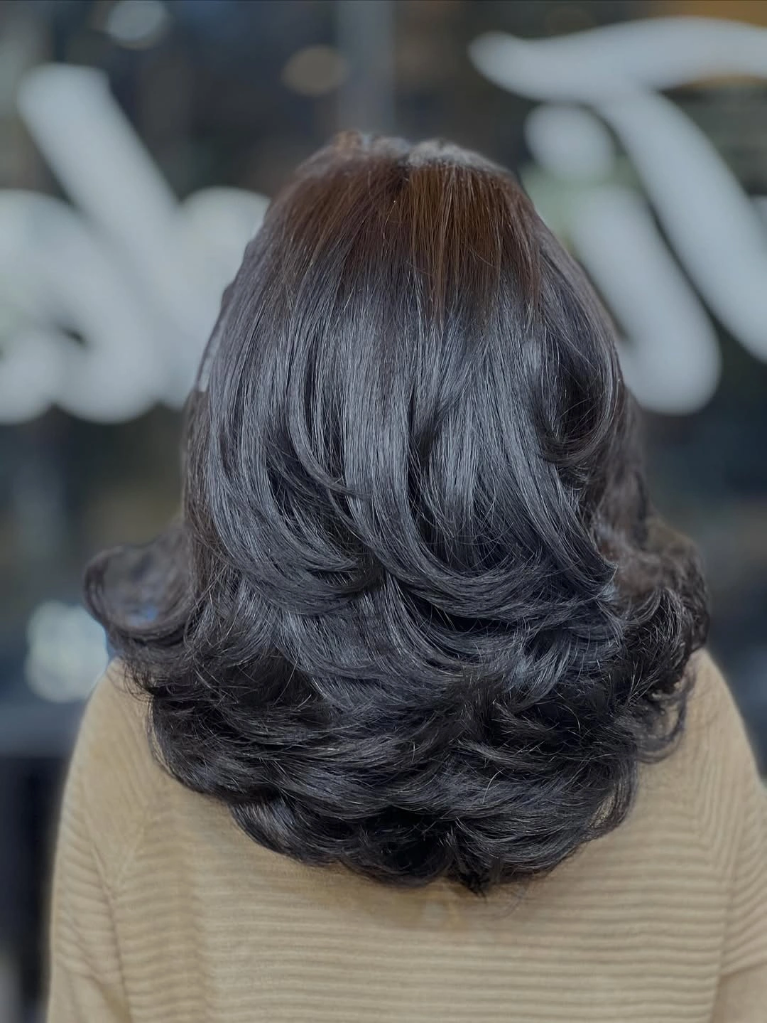 Dark medium-length hair with rounded layers and curved flipped ends