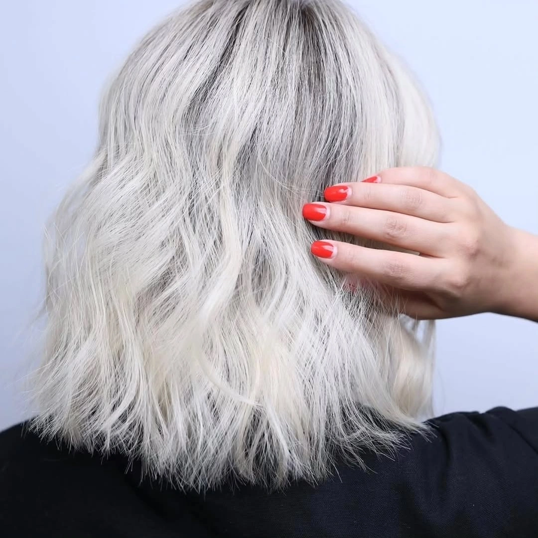 Medium length icy white blonde hair with loose waves and darker crown