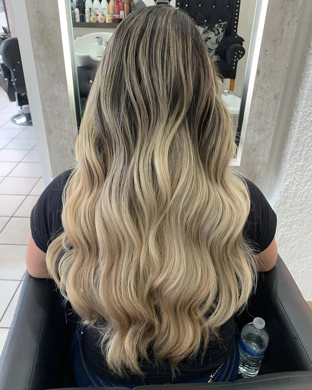 Long beige blonde waves with pronounced dark brunette roots and lighter lengths