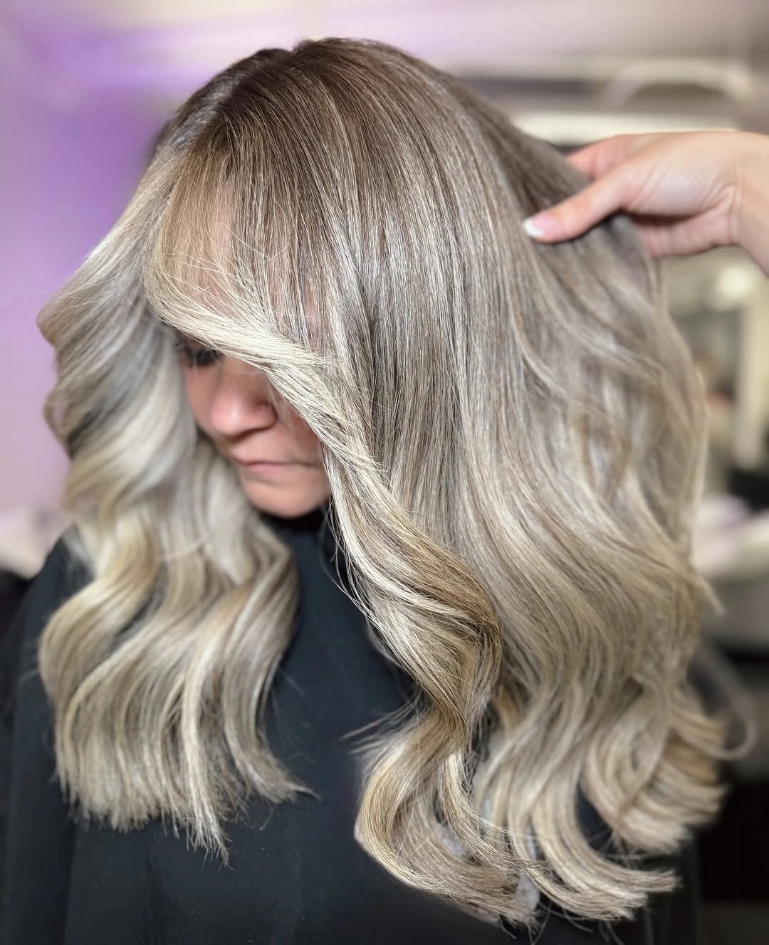 Shoulder-length ash beige blonde waves with sweeping bangs and pale face-framing strands