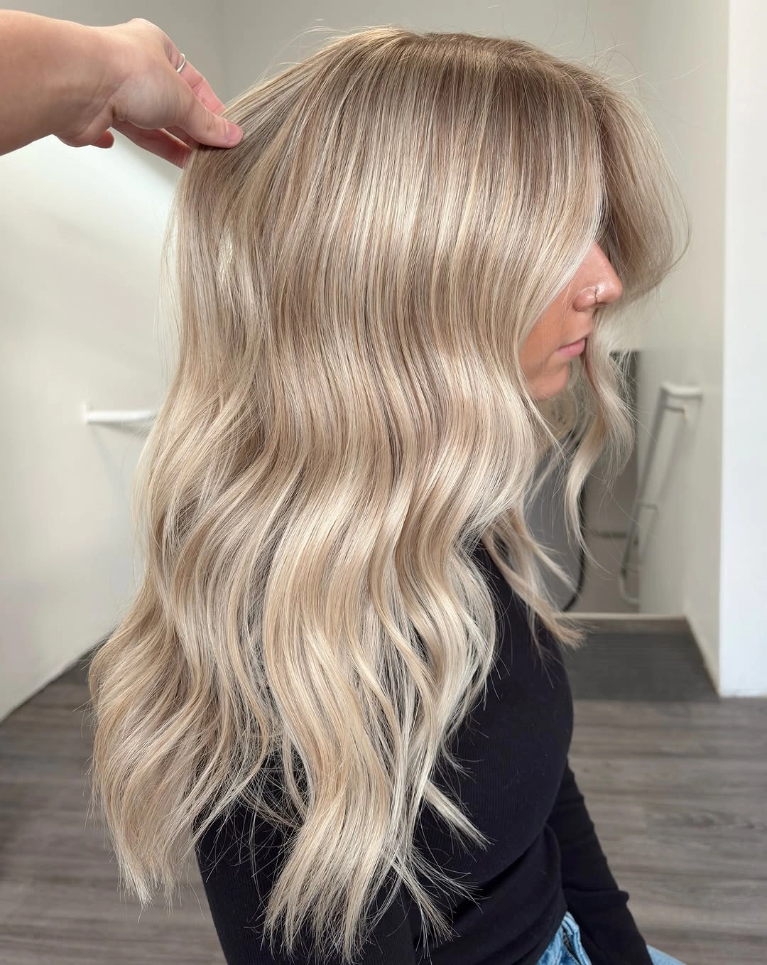 Long pale cream blonde waves with darker roots and bright face-framing sections