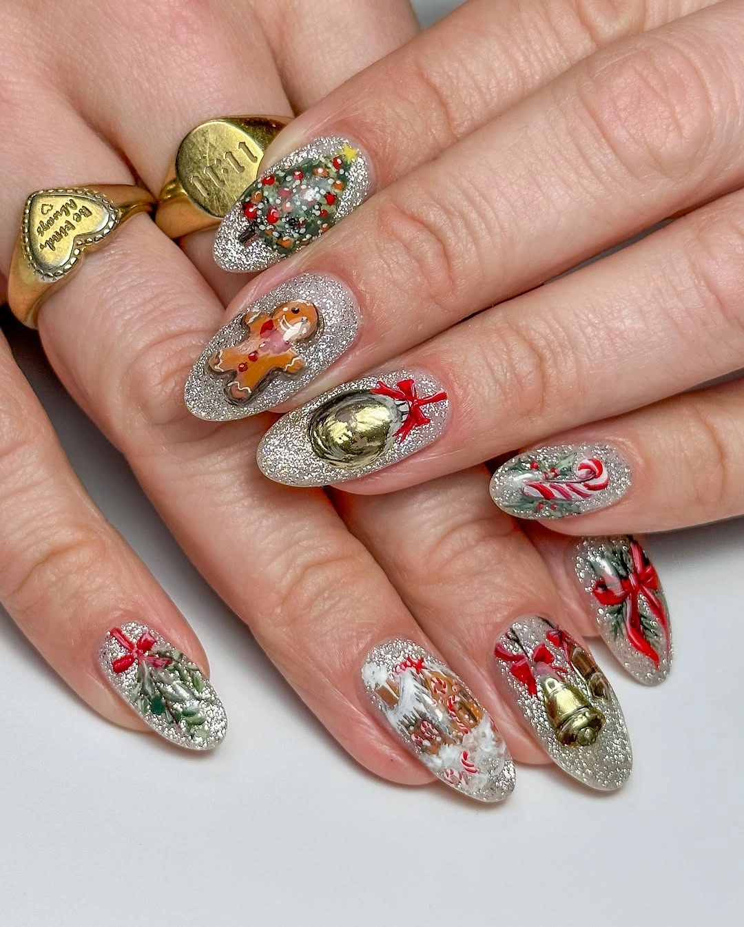 Silver glitter almond nails with gingerbread, candy canes, ornaments, and red bows