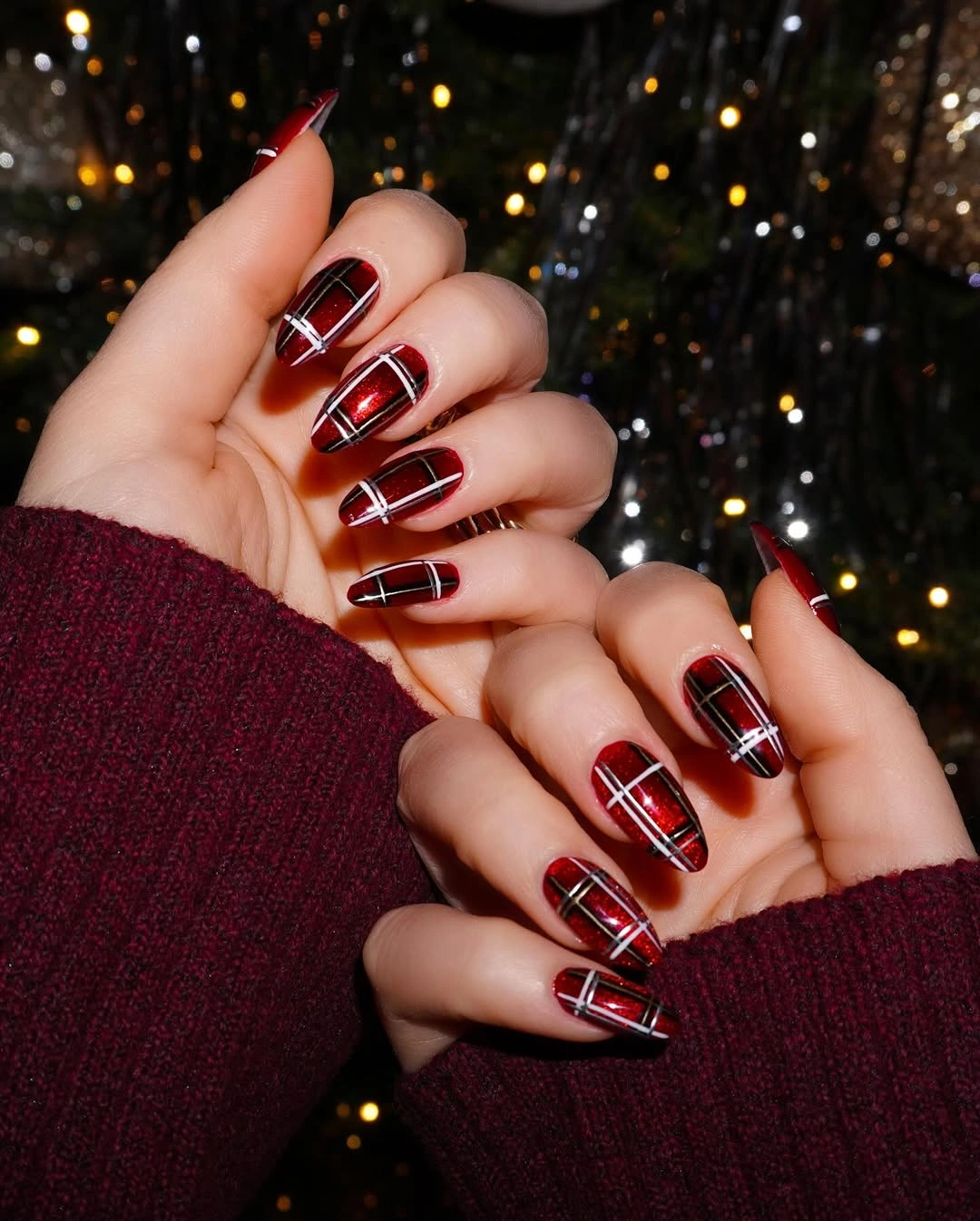Long burgundy nails with thin intersecting white lines forming windowpane patterns