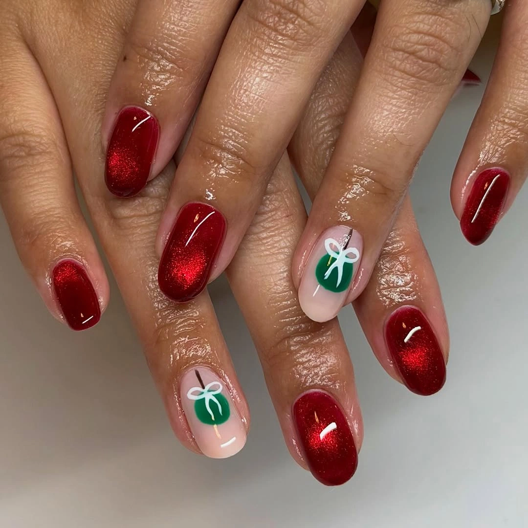 Shimmering deep red rounded nails with green ornaments and white bows