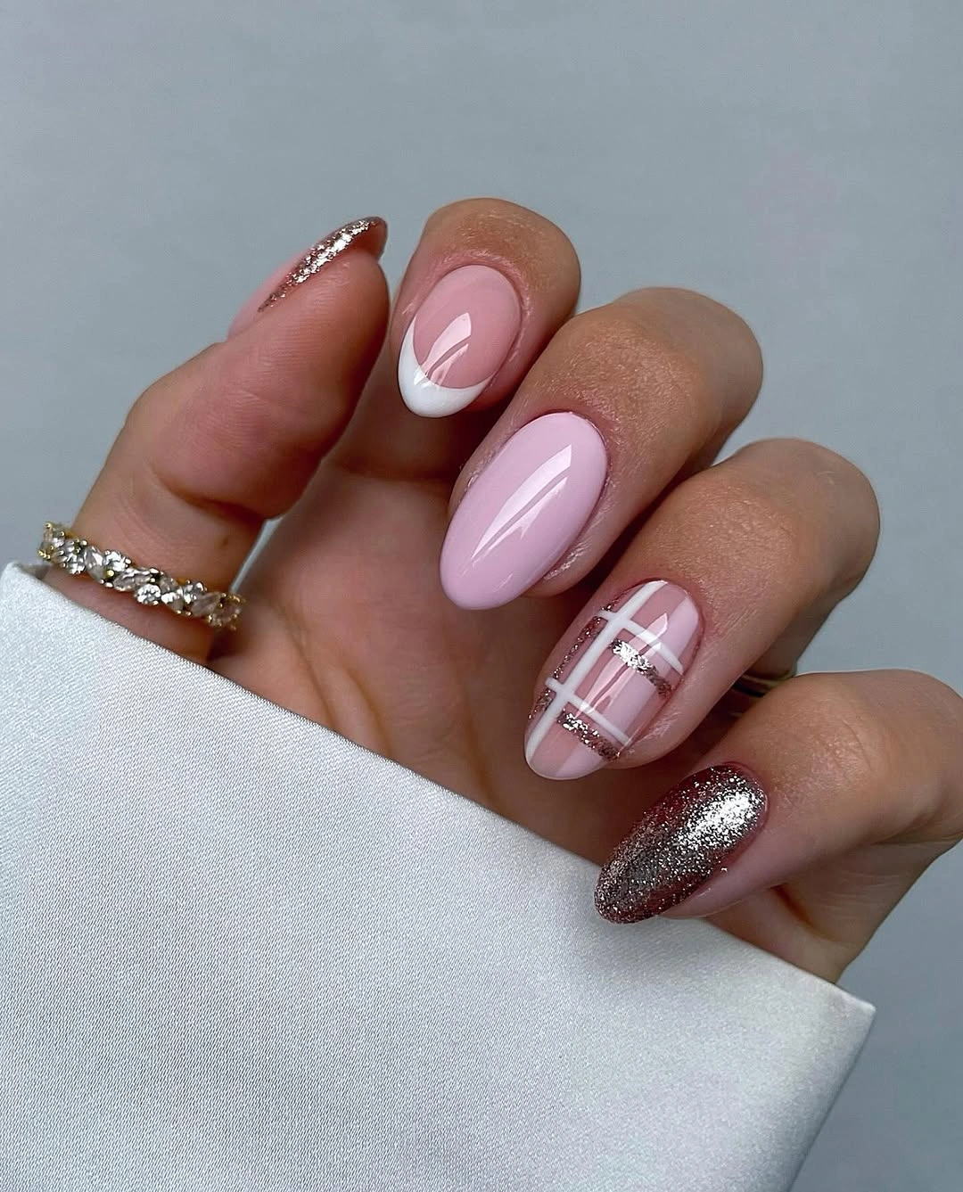 Glossy pale pink nails with curved white tips, plaid lines, and silver glitter