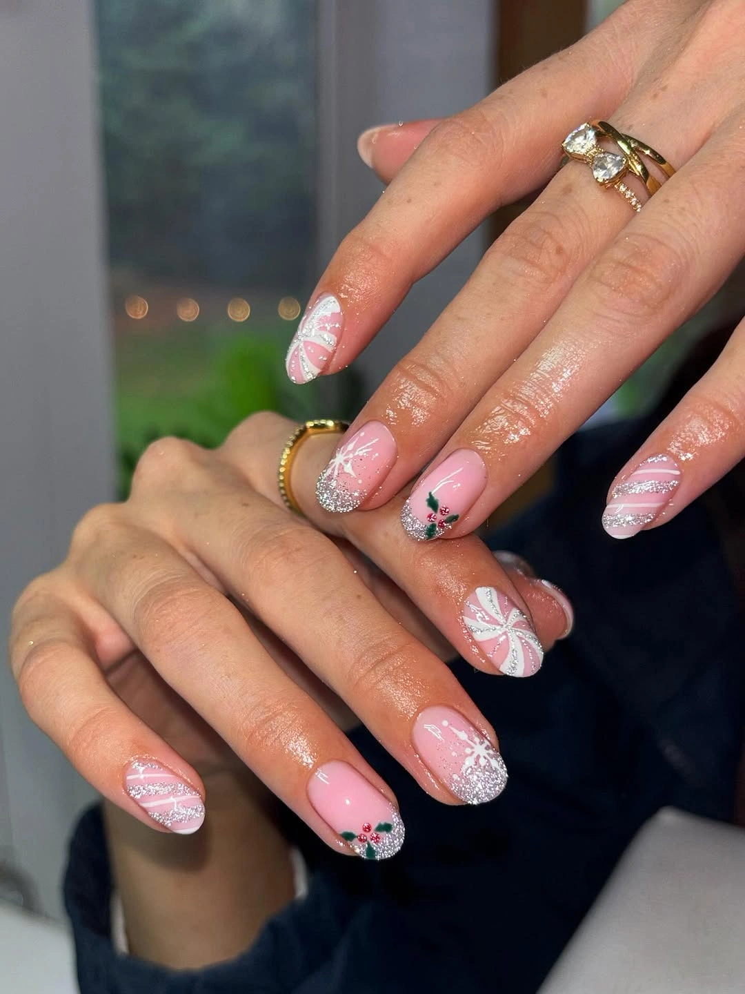 Blush pink almond nails with white curves, silver glitter, and green accents
