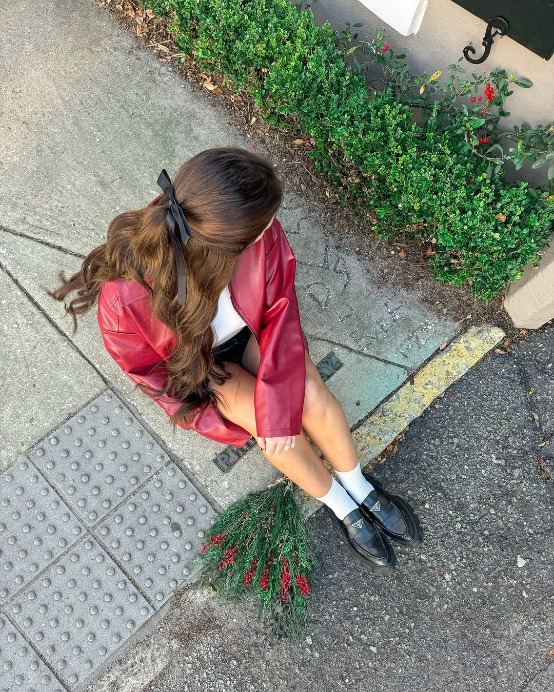 Woman in glossy red jacket, white socks, black loafers, and hair ribbon