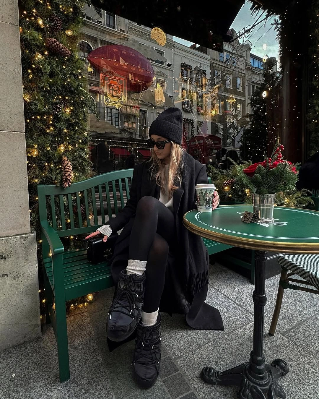 Woman in dark coat, fitted black legwear, pale socks, and lace-up boots