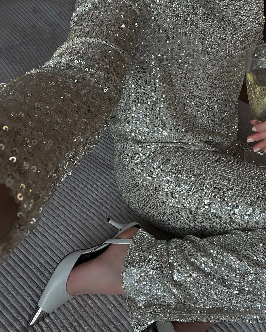 Silver sequined long-sleeved outfit with pointed slingback shoe and glass