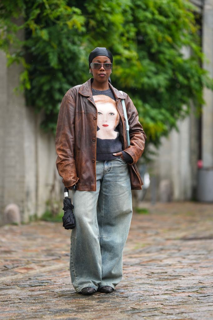 Brown Leather Jacket with Graphic Sweater and Wide-Leg Jeans — Winter Outfits for Warm Weather