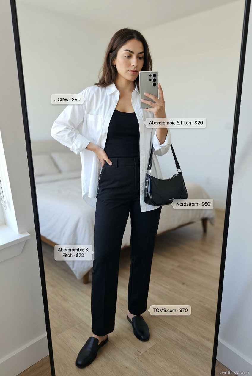 Polished white oversized button-down shirt over a black ribbed tank, essential summer outfits for tall women. Paired with tailored black trousers, black flat mules, and a structured shoulder bag for a sophisticated city stroll.