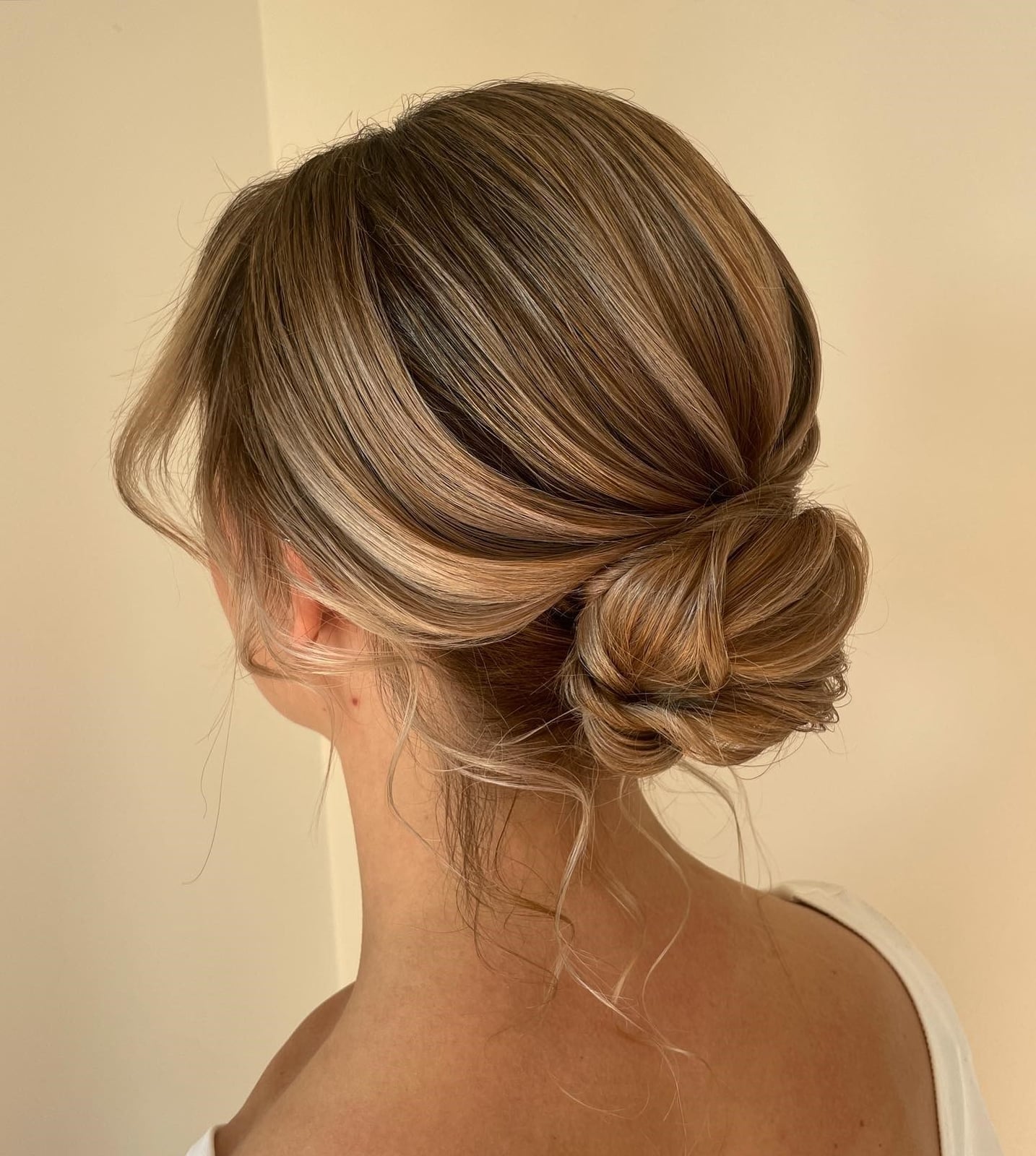 Polished Low Bun With Loose Strands — Trendy Messy Bun Updo