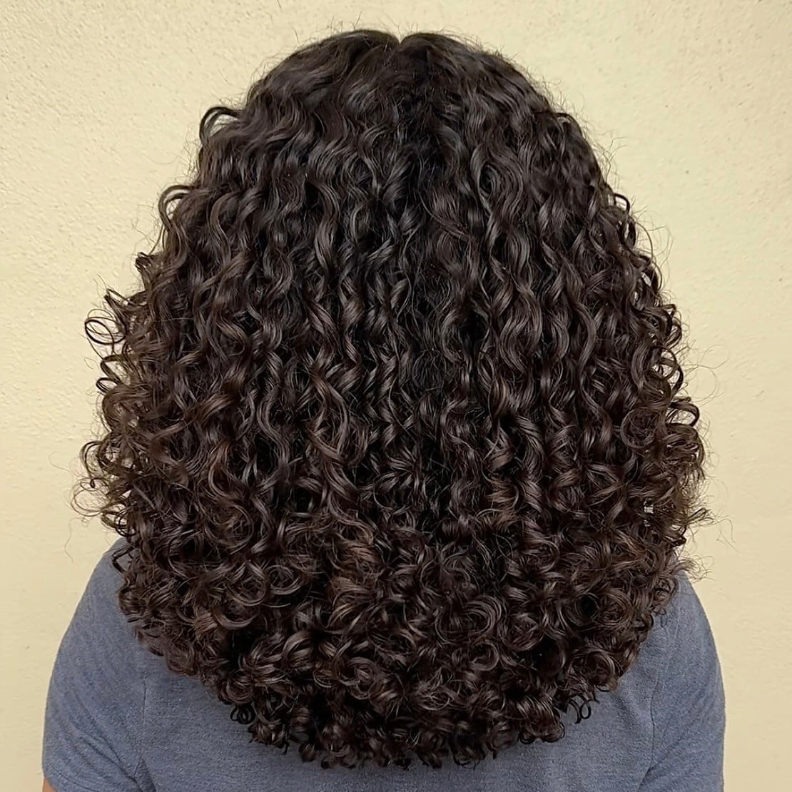 Collarbone Rounded Layers With Uniform Curls — Trendy Shoulder Length Curly Hair