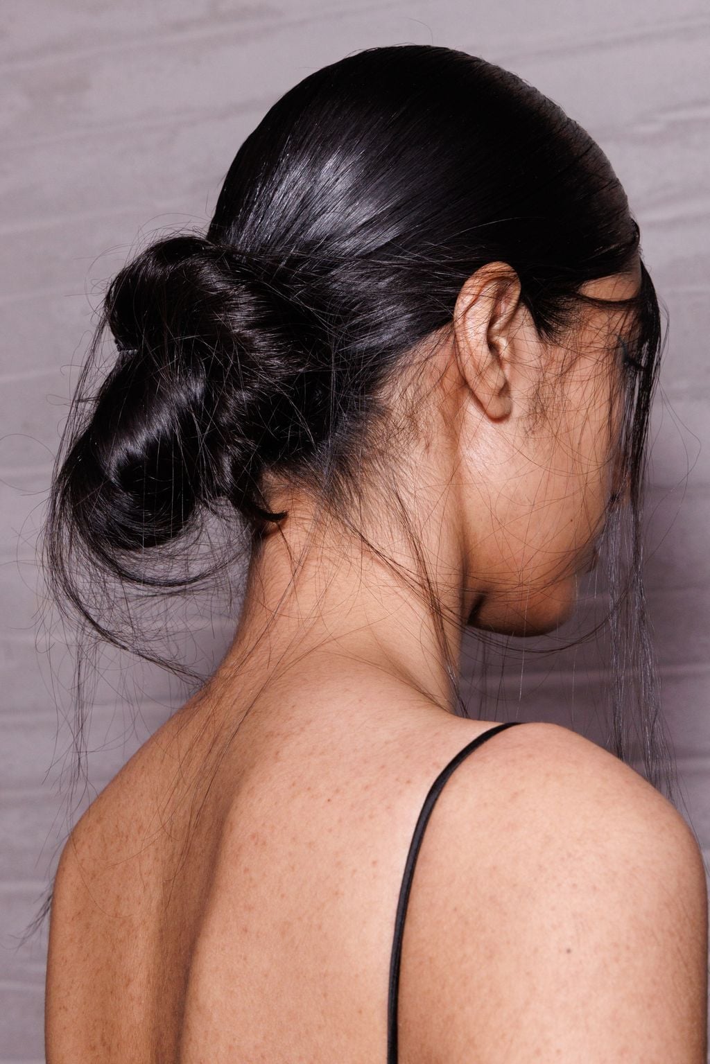 Long Dark Brown Low Neat Bun With The Hair Appears Straight And Thick — Trendy Slick Back Hairstyles