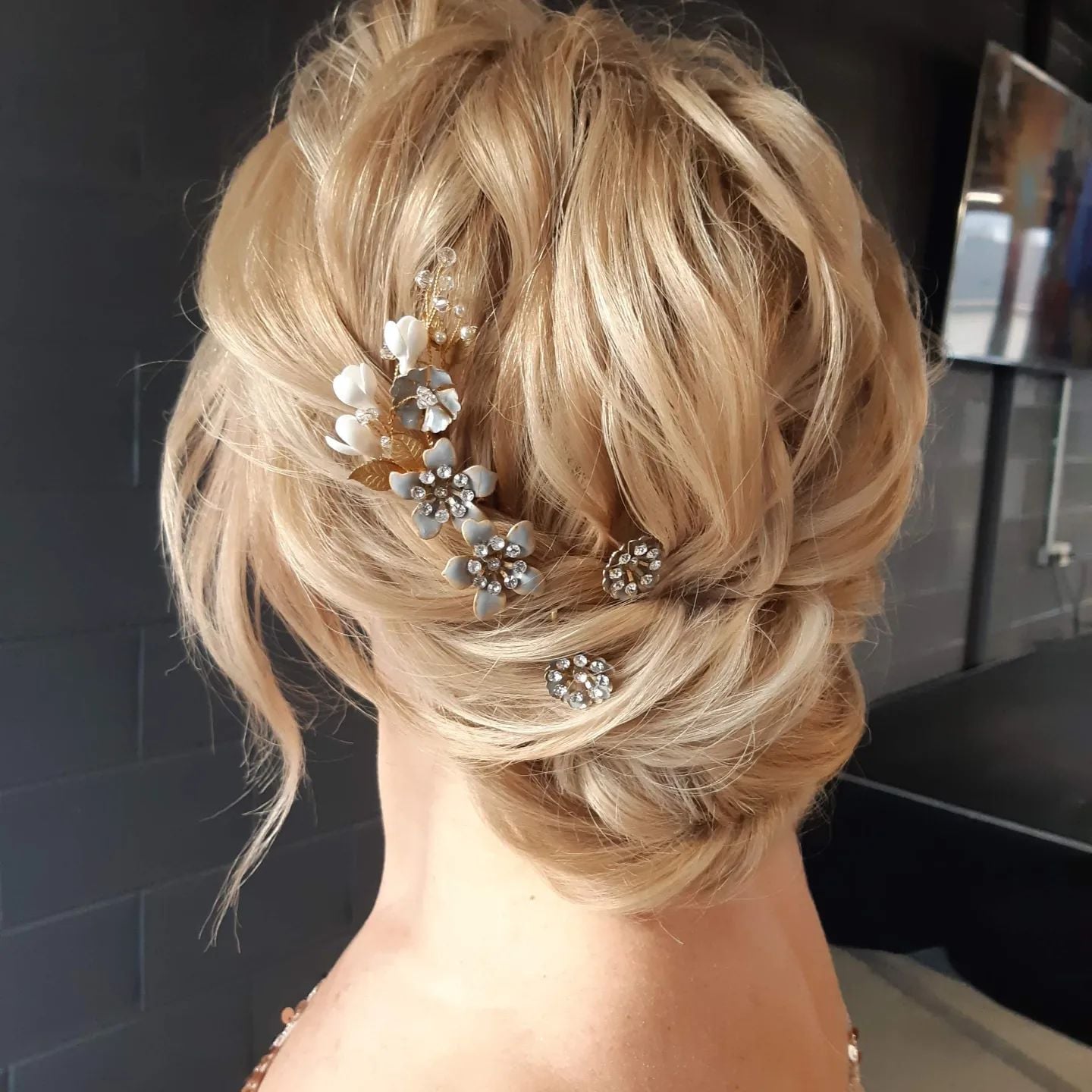 Low Braided Bun With Large Floral Accent Low Braided Bun With Large Floral Accent — Trendy Wedding Guest Updos